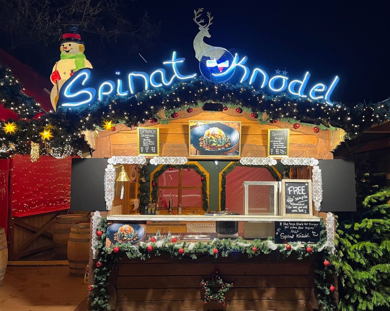 Spinat Knödel Christmas market booth with blue neon sign and festive decorations